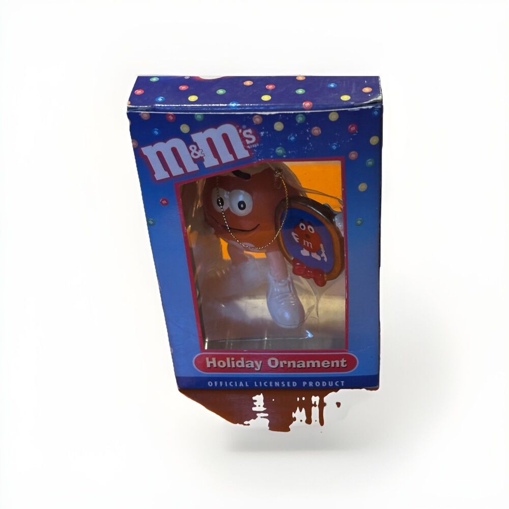M & M Orange HOLDING A FRAMED PICTURE OF RED M & M ORNAMENT KURT ADLER IN BOX